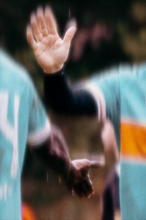 Grainy close crop of two team-mates meeting hands in a high five